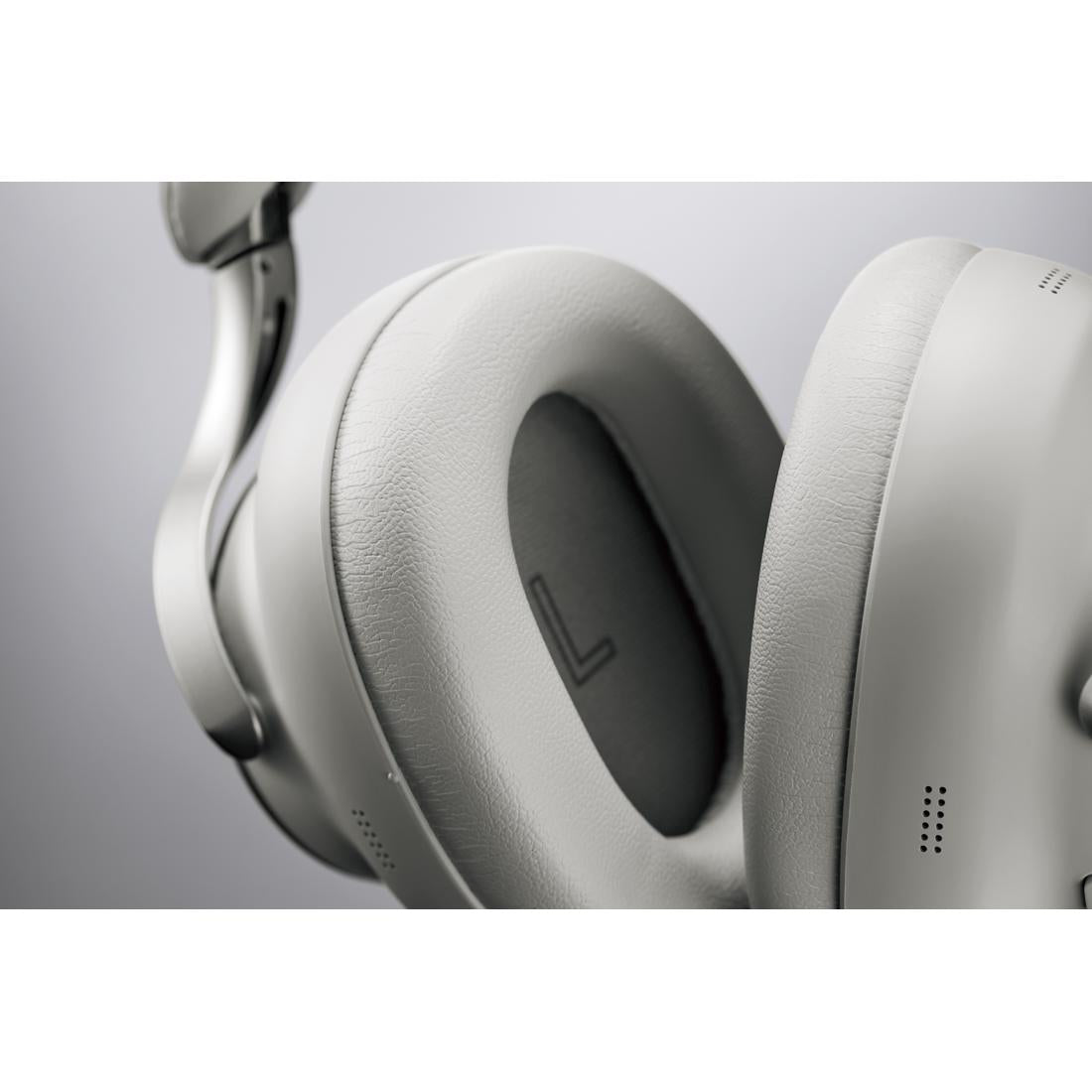 Close-up of a white over-ear headphone earcup and cushion with a visible 'L' marking on the left ear pad, set against a neutral gray background.
