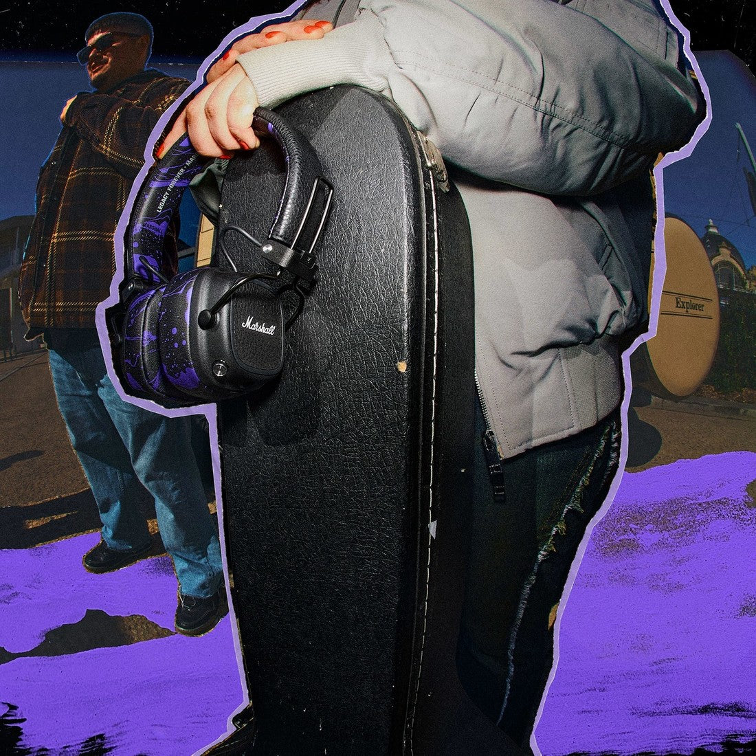 A person in a gray jacket holds a guitar case and Marshall Major V Hendrix Edition headphones.