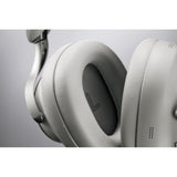 Close-up of a white over-ear headphone earcup and cushion with a visible 'L' marking on the left ear pad, set against a neutral gray background.