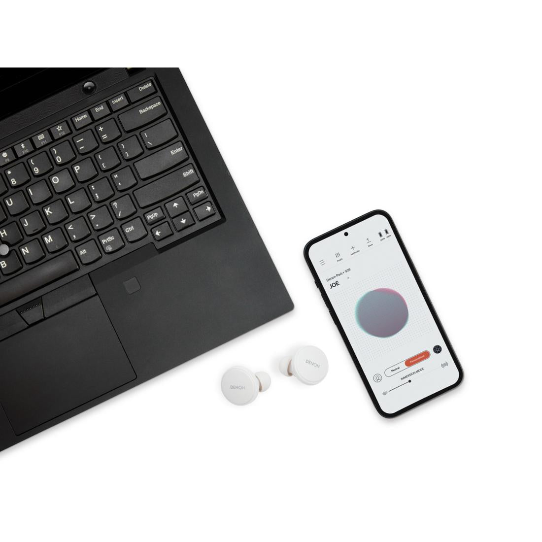 Denon White PerL Pro earbuds next to laptop and smartphone