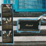 Marshall Middleton II Black and Brass portable Bluetooth speaker sits on concrete steps next to a blue metal fence.