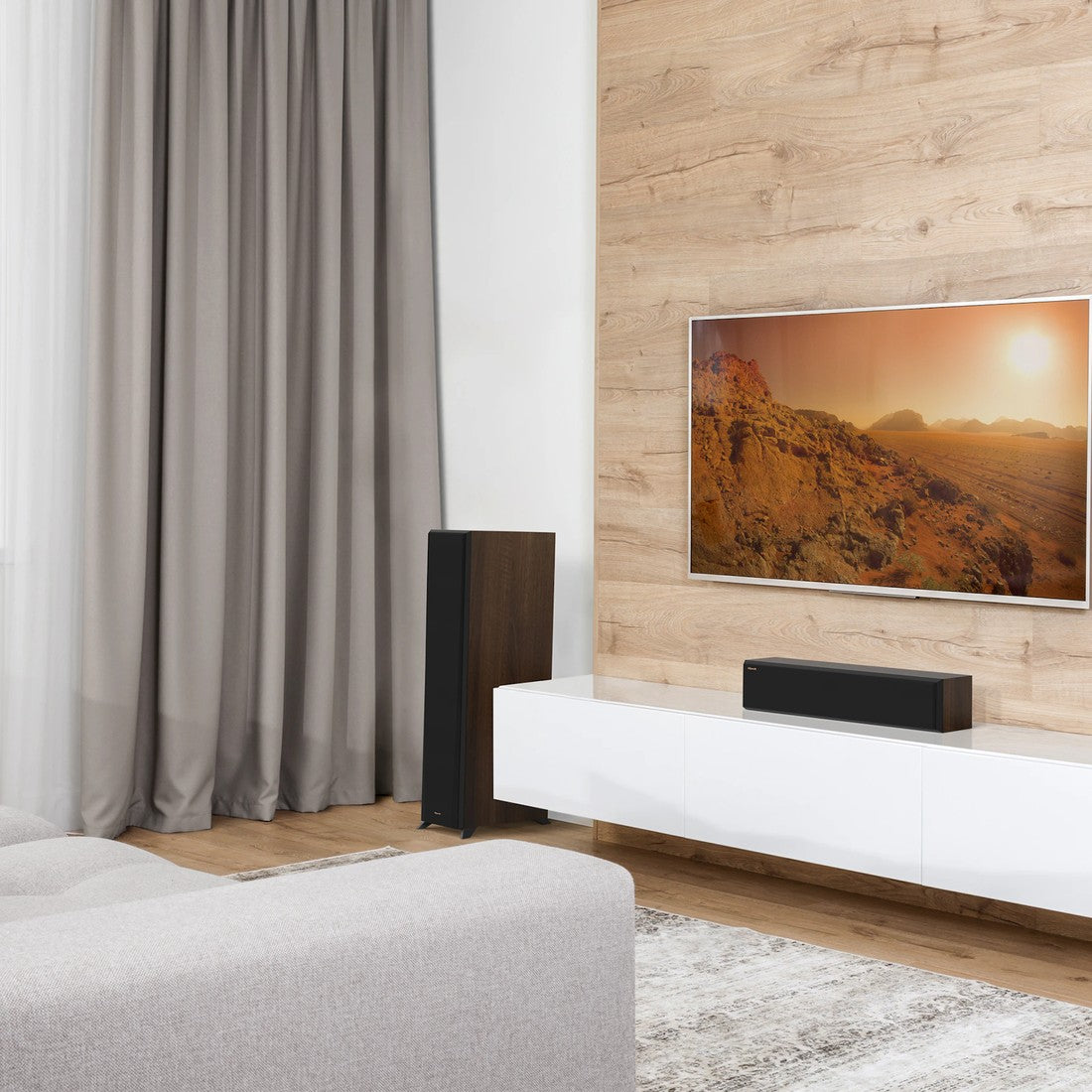 Modern living room with a TV displaying a nature scene, speakers, and a curtain.